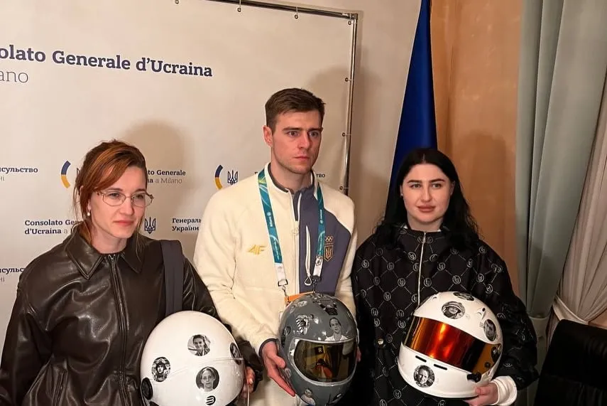 Un atleta della squadra olimpica ucraina insieme a due partecipanti al flash mob e ai caschi, al Consolato Generale d’Ucraina a Milano