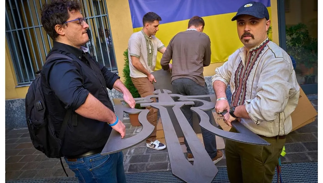 Membri dell’associazione, alcuni in camicia ricamata, reggono le parti del tridente in acciaio prima dell’installazione