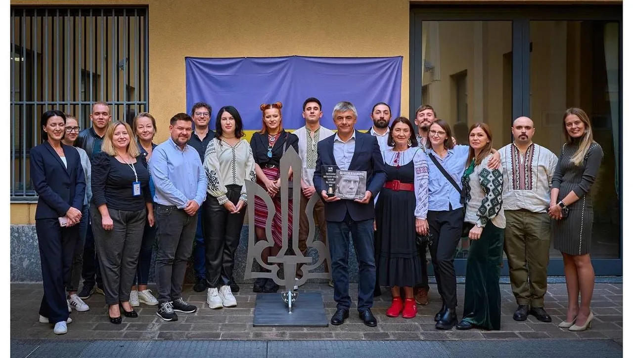 Foto di gruppo dei membri dell’associazione attorno al tridente installato nel cortile del consolato